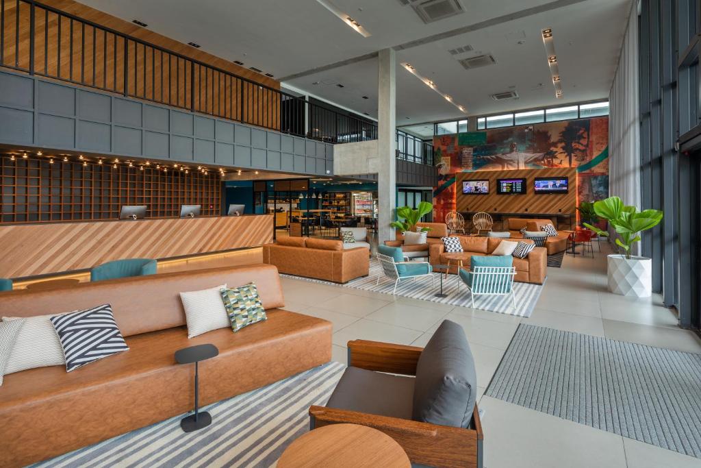 a lobby with couches and tables in a building at Linx Galeão in Rio de Janeiro
