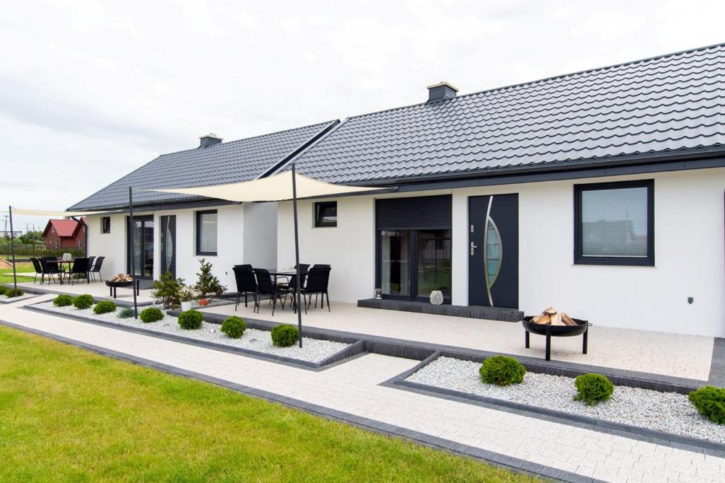 a white house with a patio and lawn at DOMKI NOWĘCIN in Łeba