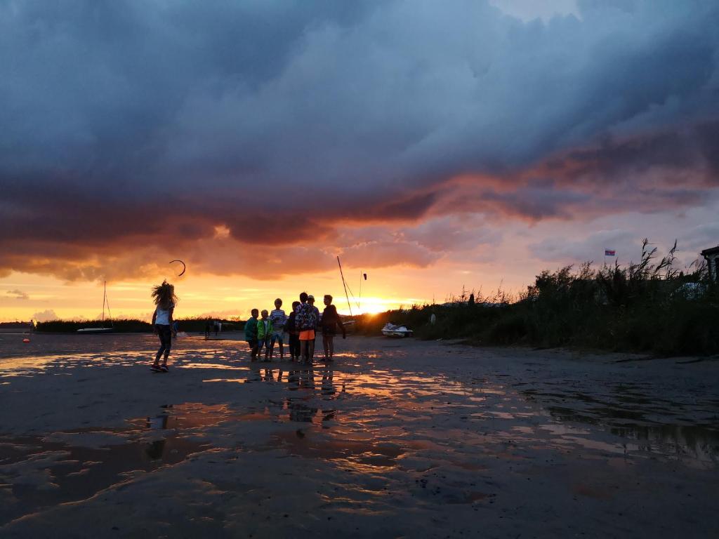 a group of people walking on the beach at sunset at Domek Holenderski Chałupy 3 Kemping in Władysławowo