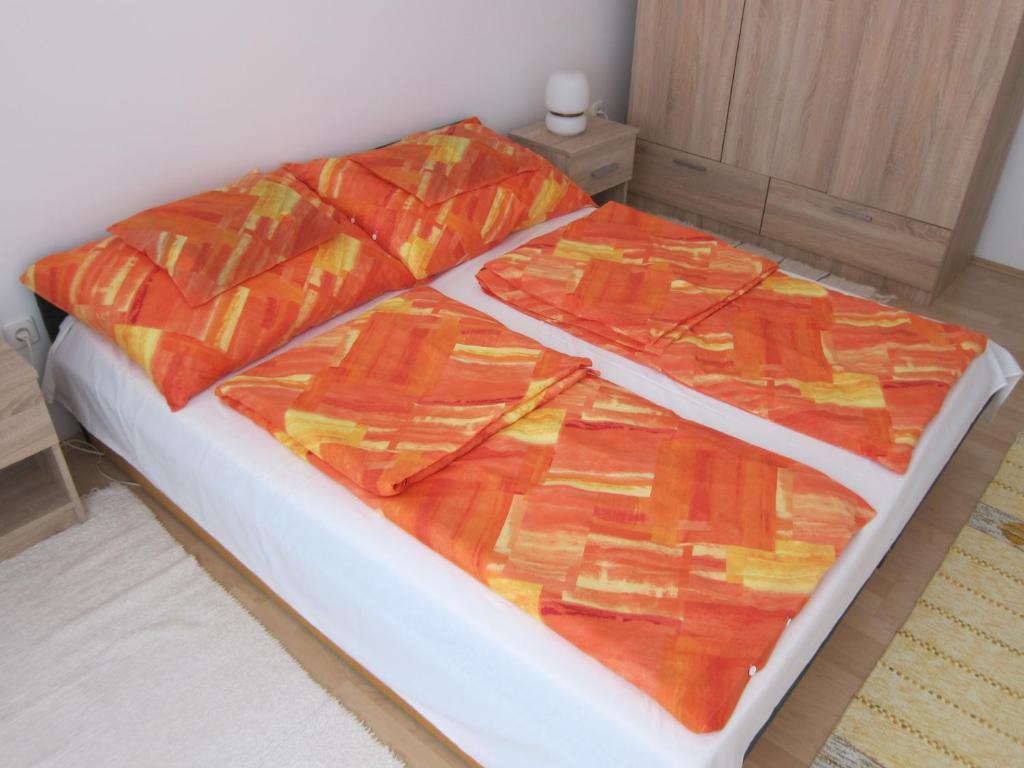 a bed with orange and yellow blankets on it at Erdélyi vendégház in Sárospatak