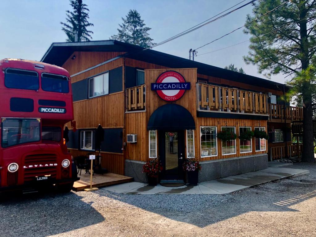 a red double decker bus parked in front of a building at Piccadilly Motel in Radium Hot Springs