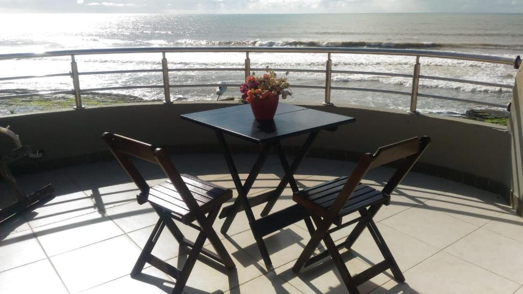 una mesa y 2 sillas en un balcón con vistas al océano en VENTO E SAL - Cobertura MAR, en Ilhéus