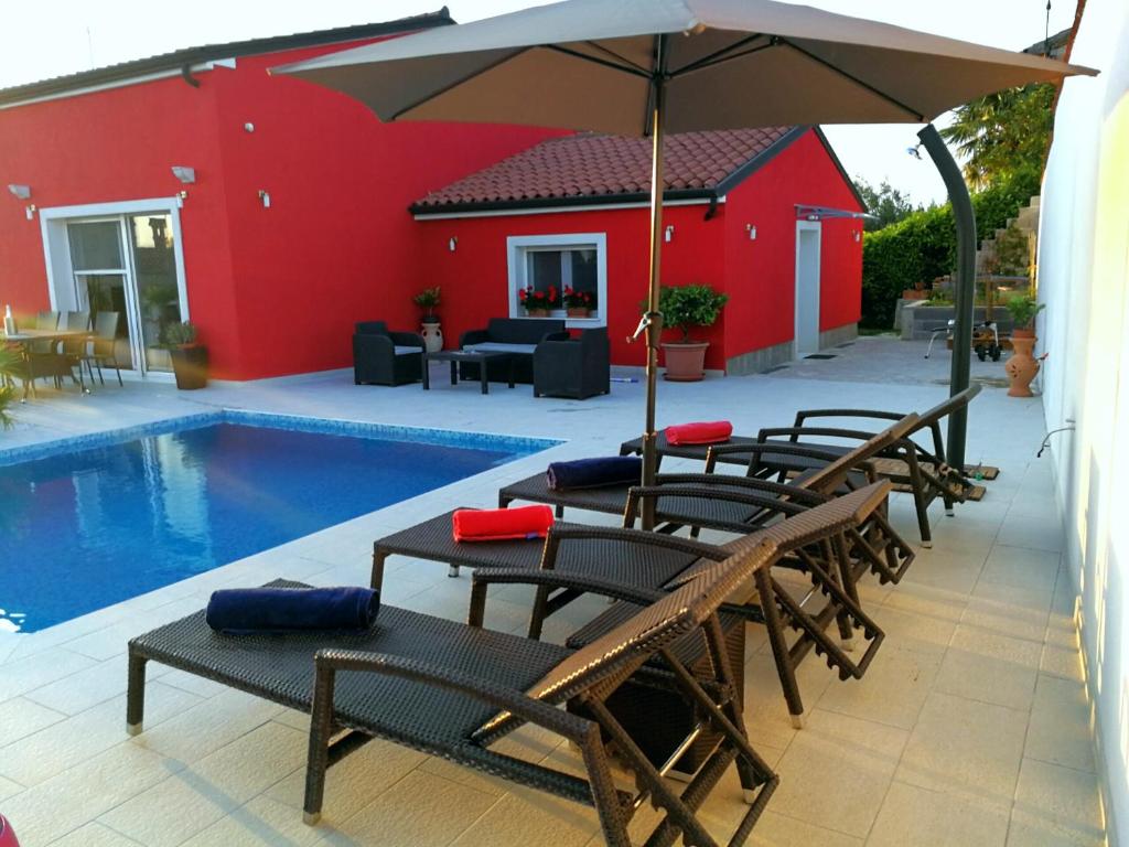 eine Gruppe Stühle und ein Sonnenschirm neben einem Pool in der Unterkunft Holiday House Anja in Buje