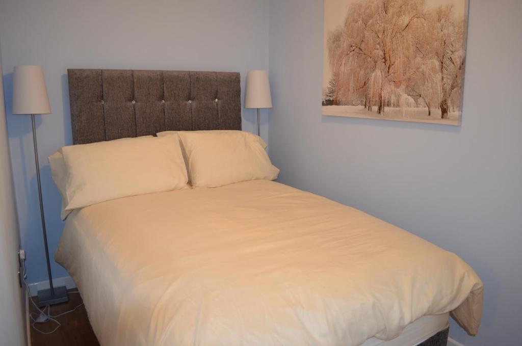 um quarto com uma cama com lençóis brancos e 2 candeeiros em Roman Villa em Bourton on the Water