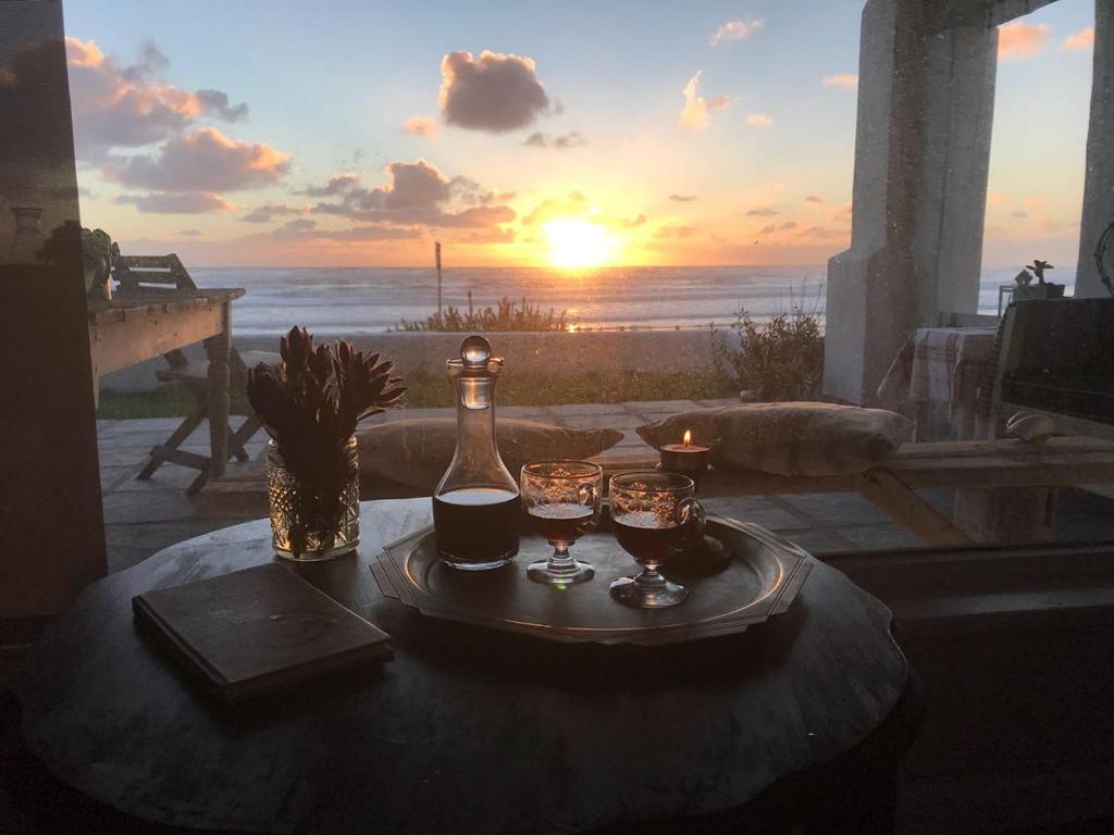 a table with a bottle of wine and two glasses on it at Dreamy Beach Room in Melkbosstrand