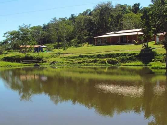 Inhaúma的住宿－Pousada Fazenda Bocaina，水体旁山丘上的房屋