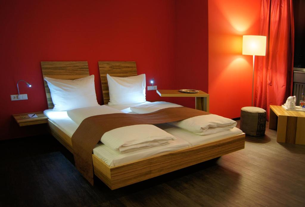 um quarto com uma cama grande e paredes vermelhas em AMH Airport-Messe-Hotel Stuttgart em Filderstadt