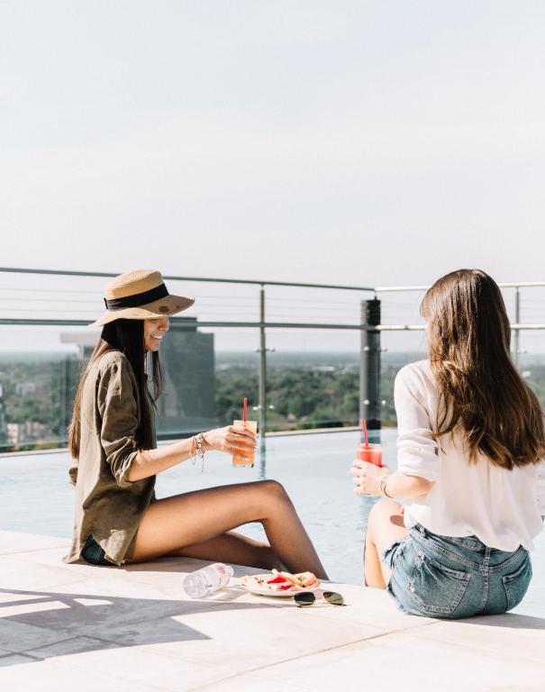 two women sitting on the floor with drinks at Hub Hotel Asuncion in Asuncion