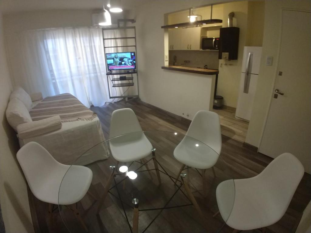 sala de estar con mesa y 4 sillas blancas en Departamento Centrico en Rosario