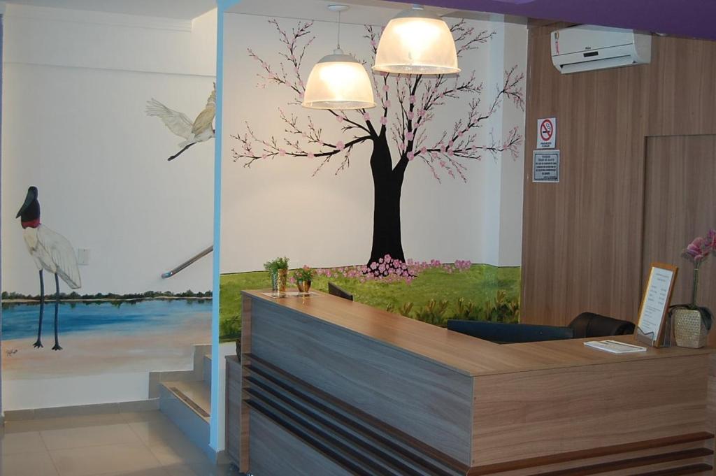 a reception desk with a tree mural on the wall at Aeroporto Plaza Hotel in Campo Grande