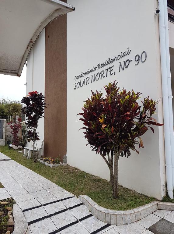una señal en el lateral de un edificio con una planta en solar norte, en Florianópolis
