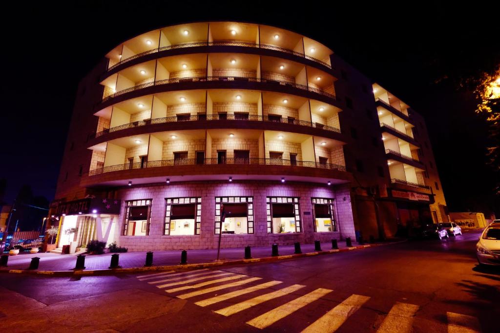ein großes Gebäude in der Nacht mit lila Lichtern in der Unterkunft Ritz Hotel in Jerusalem