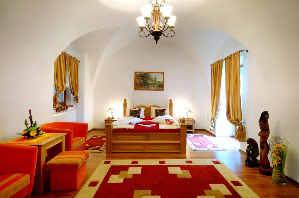 een slaapkamer met een bed, een bank en een kroonluchter bij Apartmanovy Dom Martha a Domček Martuška in Liptovský Ján