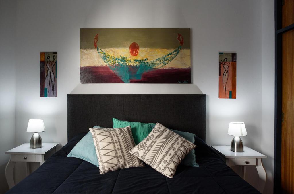 Un dormitorio con una cama con una pintura encima. en Apartamento Inmejorable Ubicacion en Córdoba