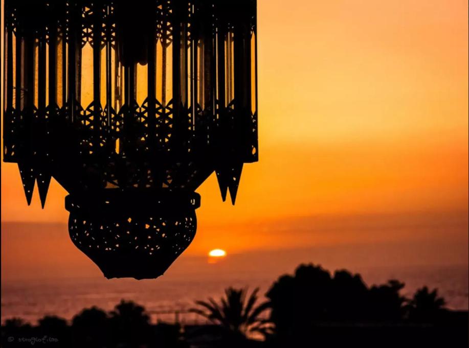 um lustre com o pôr-do-sol ao fundo em Apartment in Playa de las Americas 1 em Playa de las Americas