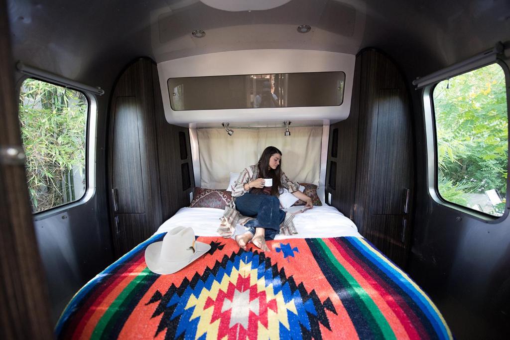 a woman sitting on a bed in a van at Caravan Outpost in Ojai