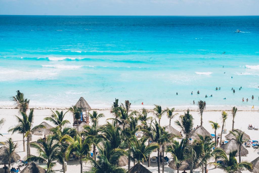 an aerial view of a beach with palm trees and the ocean at Hotel NYX Cancun in Cancún
