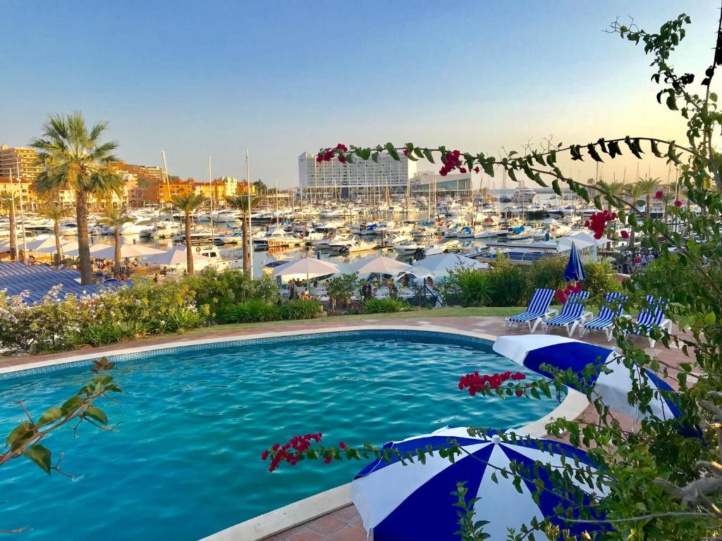 a pool with umbrellas and a marina with boats at Marina Garden by Ethnic Ocean in Vilamoura