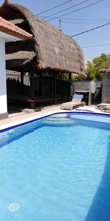 a large blue swimming pool with a thatch roof at Izaac's Bed & Breakfast in Lovina