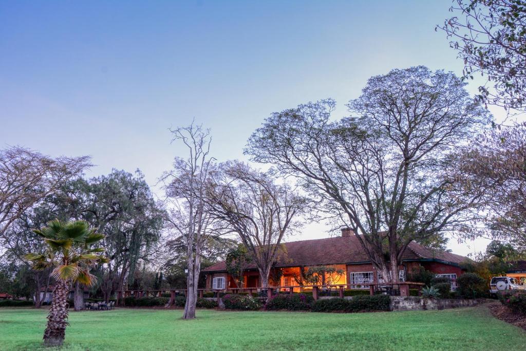 a house in the middle of a yard with trees at Jacaranda Lake Elementeita Lodge in Gilgil