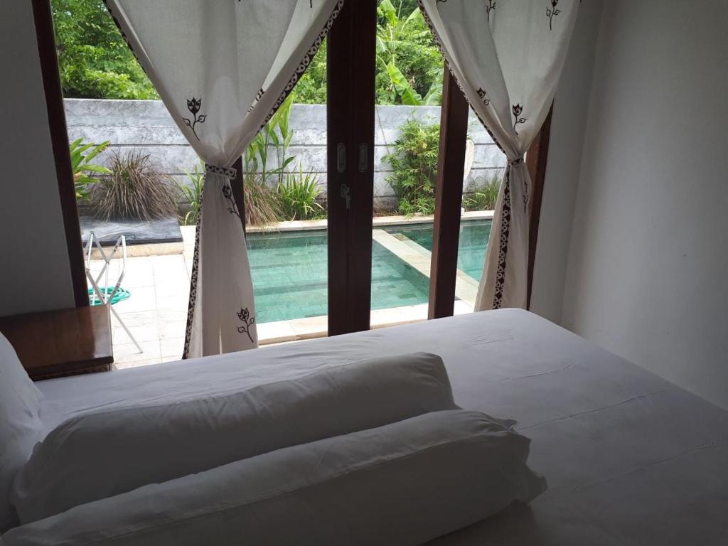a bedroom with a bed and a window with a pool at Villa das Meer 2BR Villa near Lovina Beach in Lovina