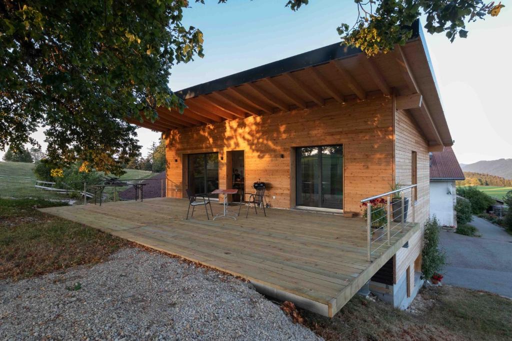 een groot houten terras aan de zijkant van een huis bij Au Chant du Vent in Tramelan