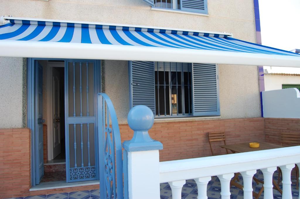 ein Haus mit einer blauen und weißen Markise und einer Veranda in der Unterkunft CASA CON VISTAS AL MAR EN LA PUNTA DEL CAIMÁN (ISLA CRISTINA) in Isla Cristina