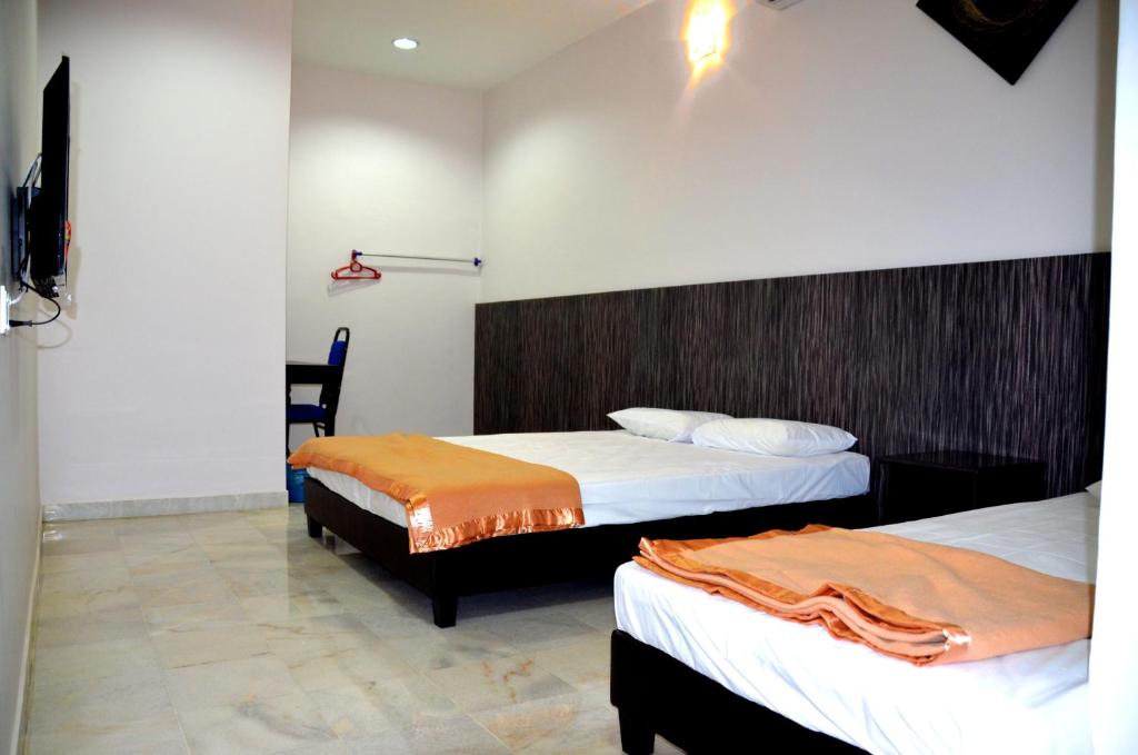 a hotel room with two beds and a chair at Homestay Klebang Ipoh in Ipoh