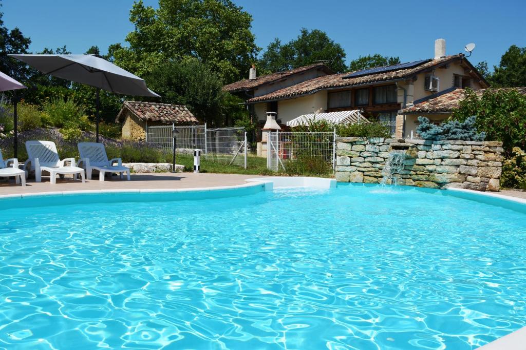 uma piscina num quintal com duas cadeiras e uma casa em Gîte Bois et Senteurs em Lafrançaise