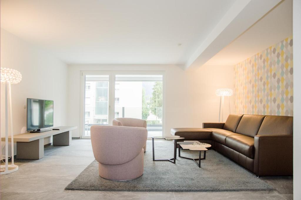 a living room with a couch and a tv at Apartment JungfrauCenter Bällenhöchst - GriwaRent AG in Interlaken