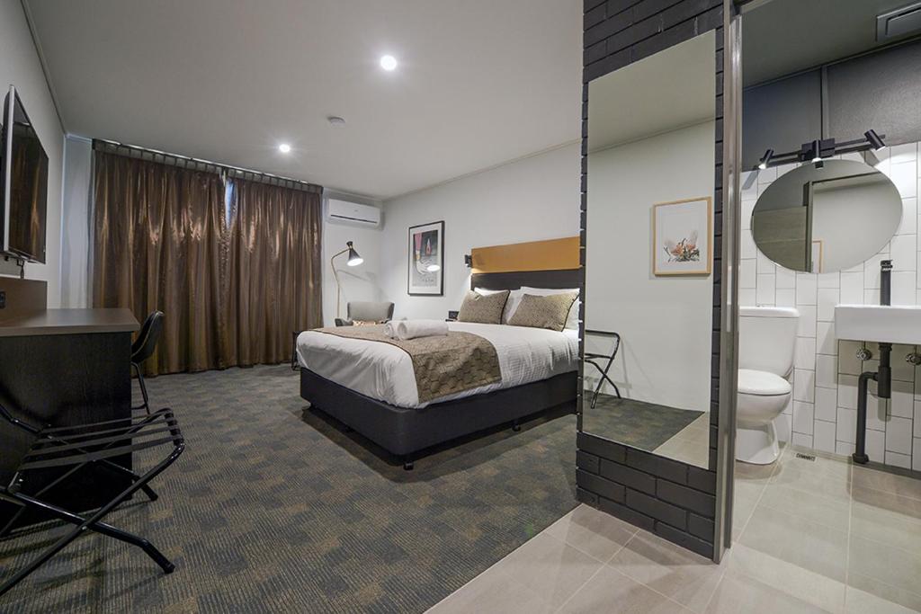a hotel room with a bed and a bathroom at CBD Motor Inn in Coffs Harbour