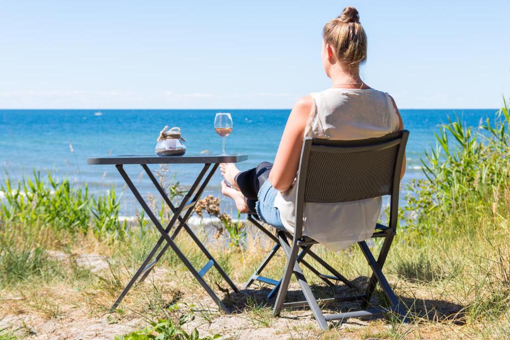 a woman sitting at a table with a glass of wine at Meiks Ostseehütten in Dranske