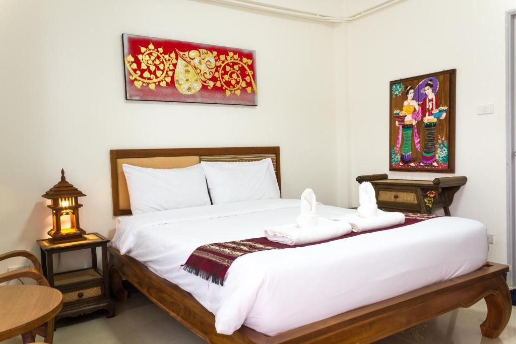 um quarto com uma cama branca com duas toalhas em DPHouse center of Old Chiang Mai em Chiang Mai