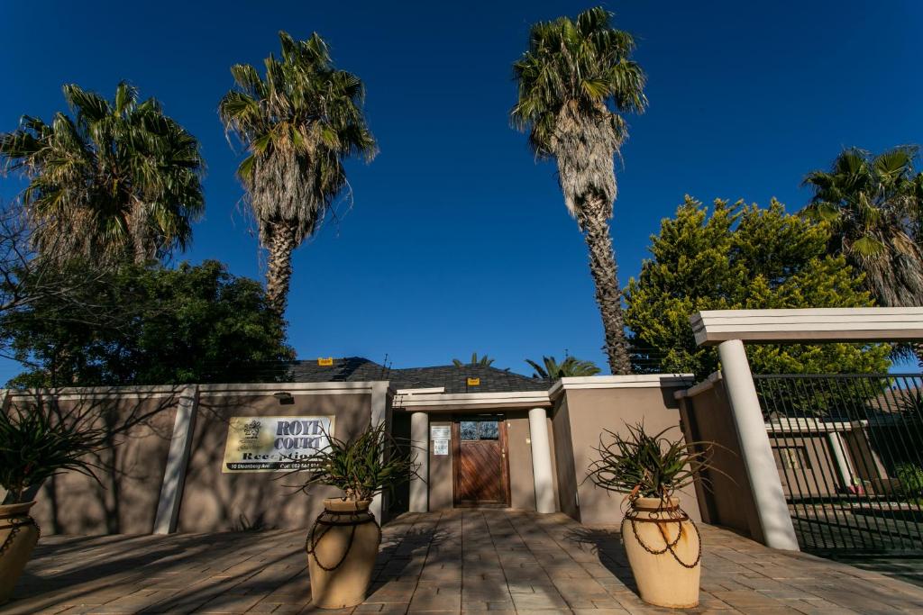 a building with palm trees in the background at Royl Court Guesthouse in Kimberley