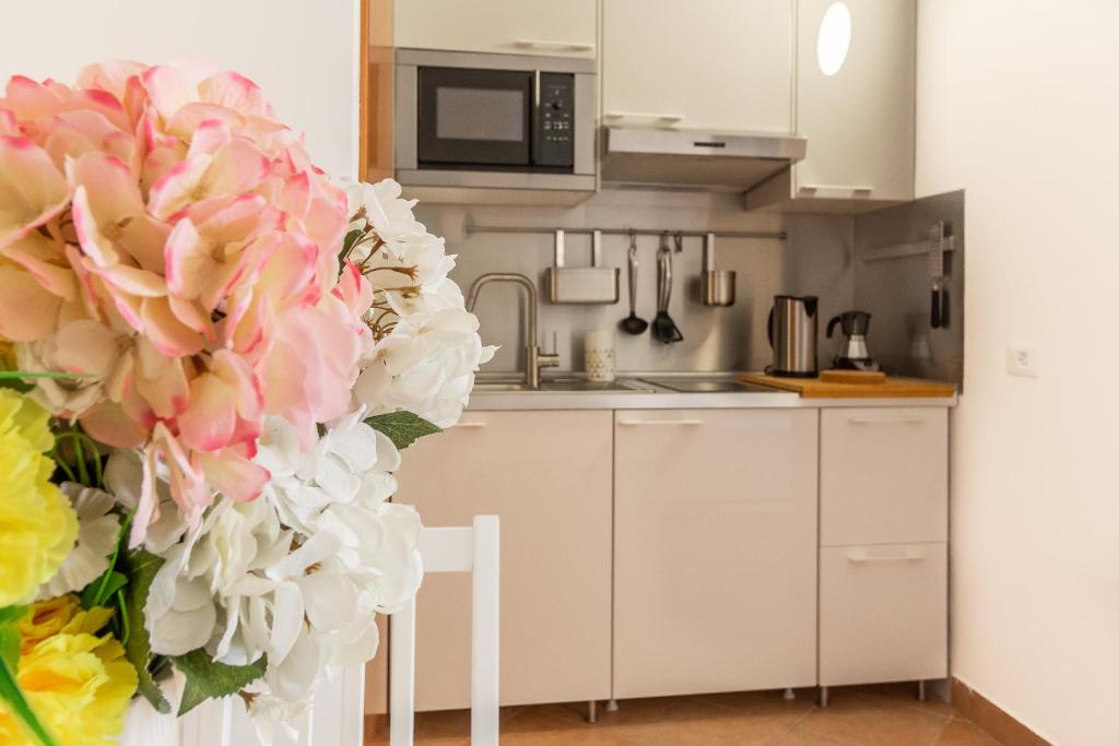 una cocina con un jarrón de flores rosas y blancas en Alessia's Flat - Affori, en Milán