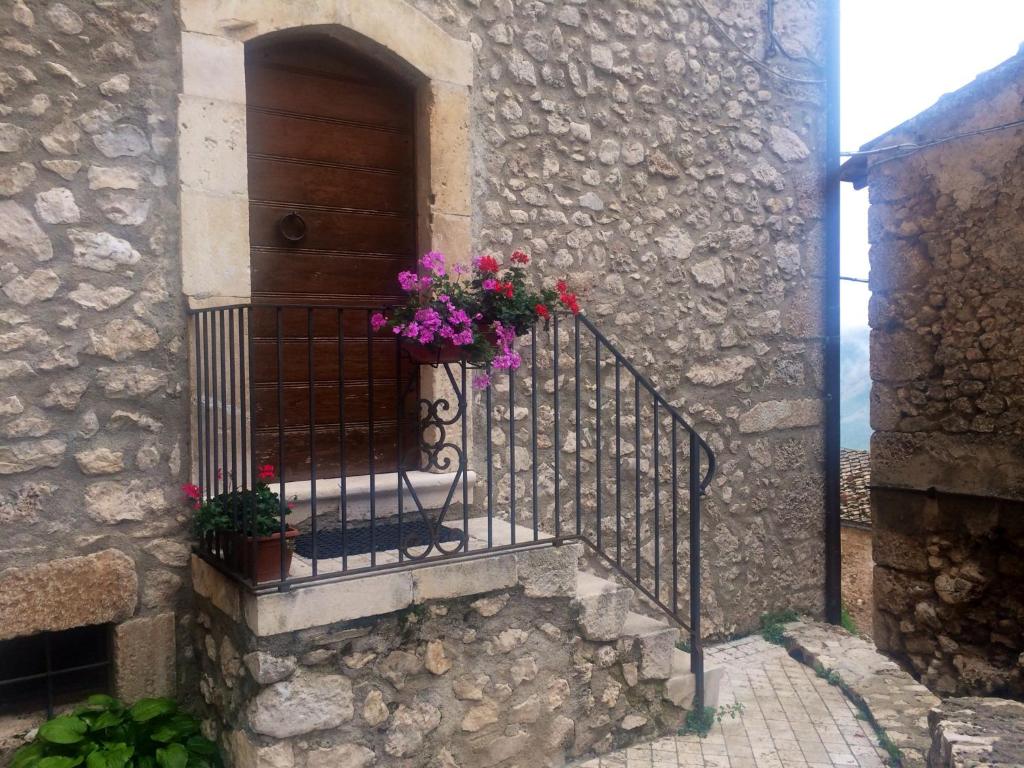 - un bâtiment en pierre avec un escalier fleuri dans l'établissement Casa a Santo Stefano di Sessanio, à Santo Stefano di Sessanio