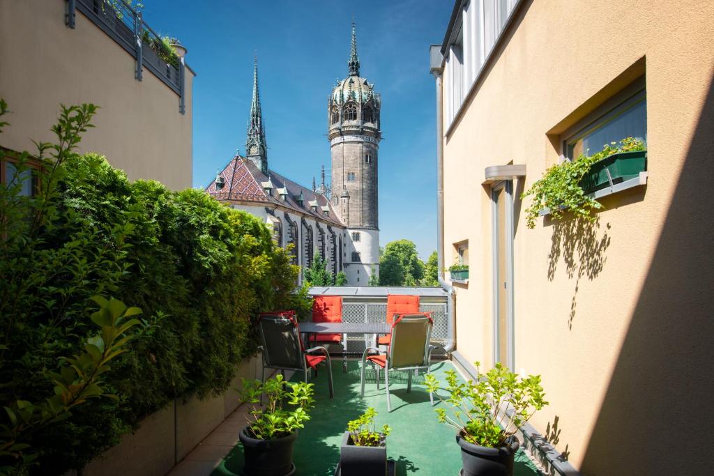 un patio con sillas y un edificio con una torre de reloj en Ferienwohnungen am Schloss en Lutherstadt Wittenberg