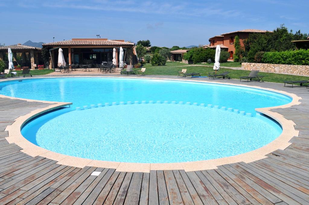 uma grande piscina azul com um deque de madeira em Cala Paradiso Residence em San Teodoro