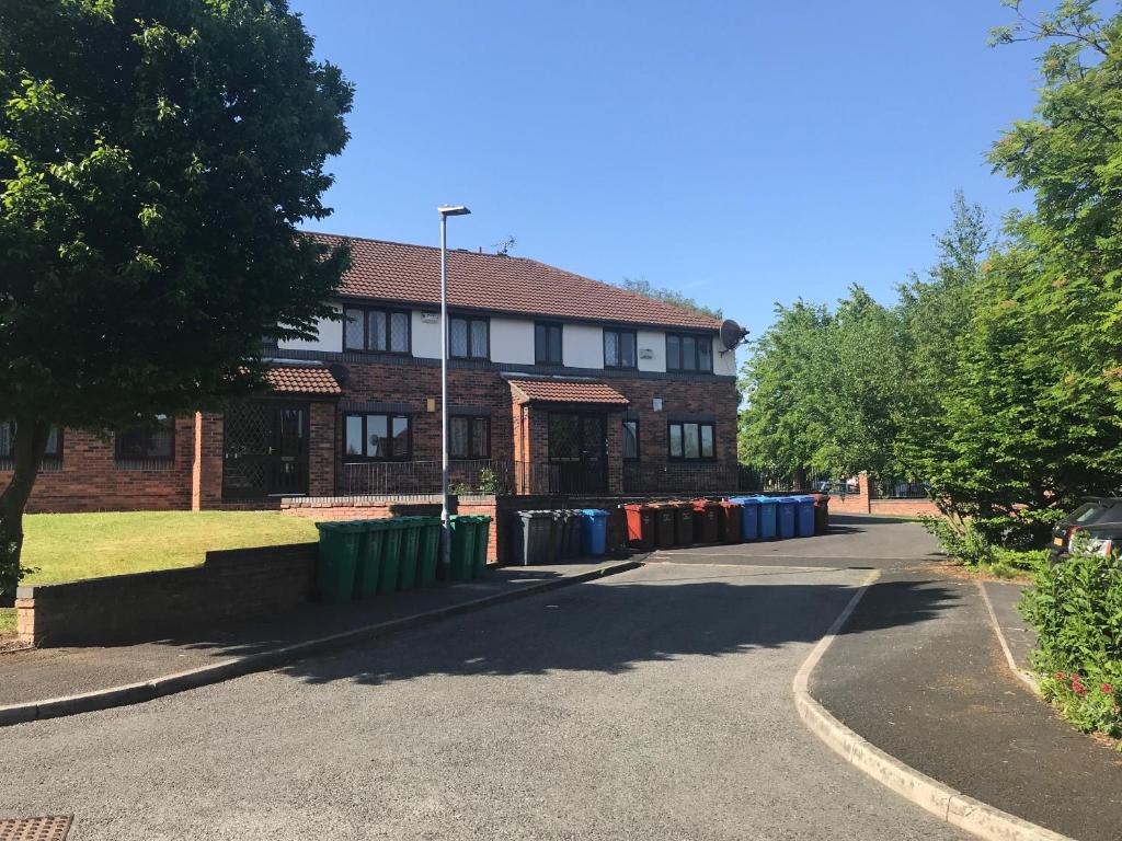 un edificio con una fila de cubos de basura delante de él en Flat 9a Badby Close, en Mánchester