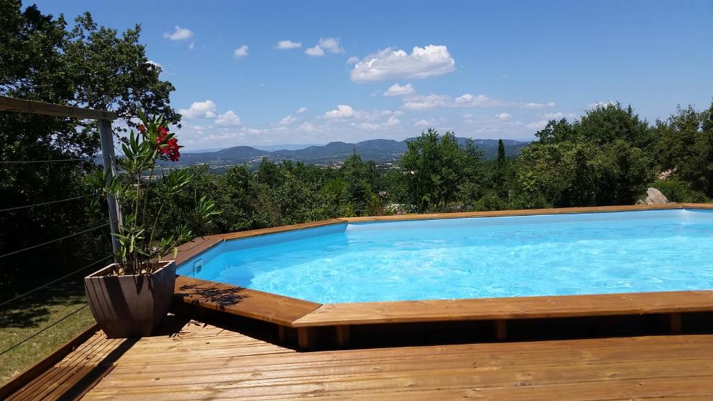 a large swimming pool on a wooden deck with a view at Lou Mazet in Saint-Privat-de-Champclos