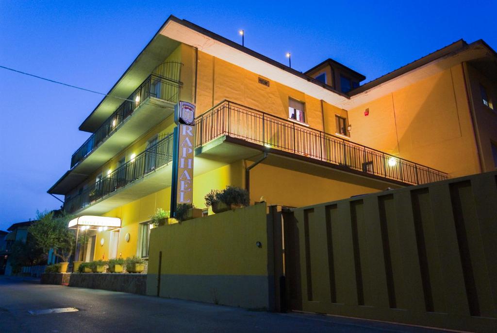 een groot gebouw met een hek ervoor bij Hotel Raphael in Montecatini Terme