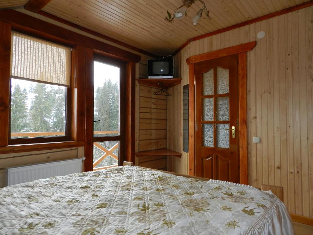 a bedroom with a bed and a tv and windows at Barvy Karpat in Slavske