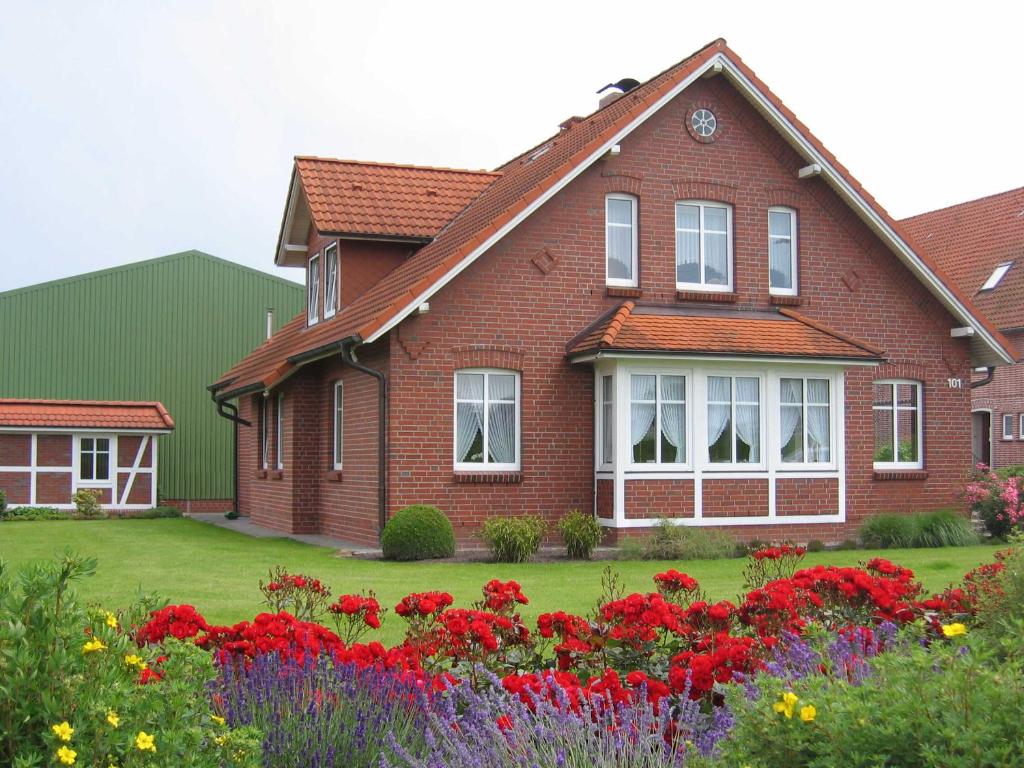 Obsthof Fock في Mittelnkirchen: منزل من الطوب الأحمر مع الزهور في الفناء