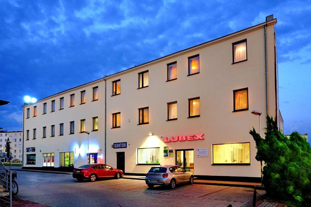 a large white building with cars parked in a parking lot at Noclegi w Lublińcu Lubex in Lubliniec