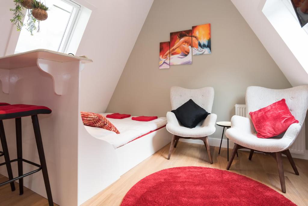 een kamer met 2 stoelen en een rood tapijt bij Saint Claire Studio's in Amsterdam