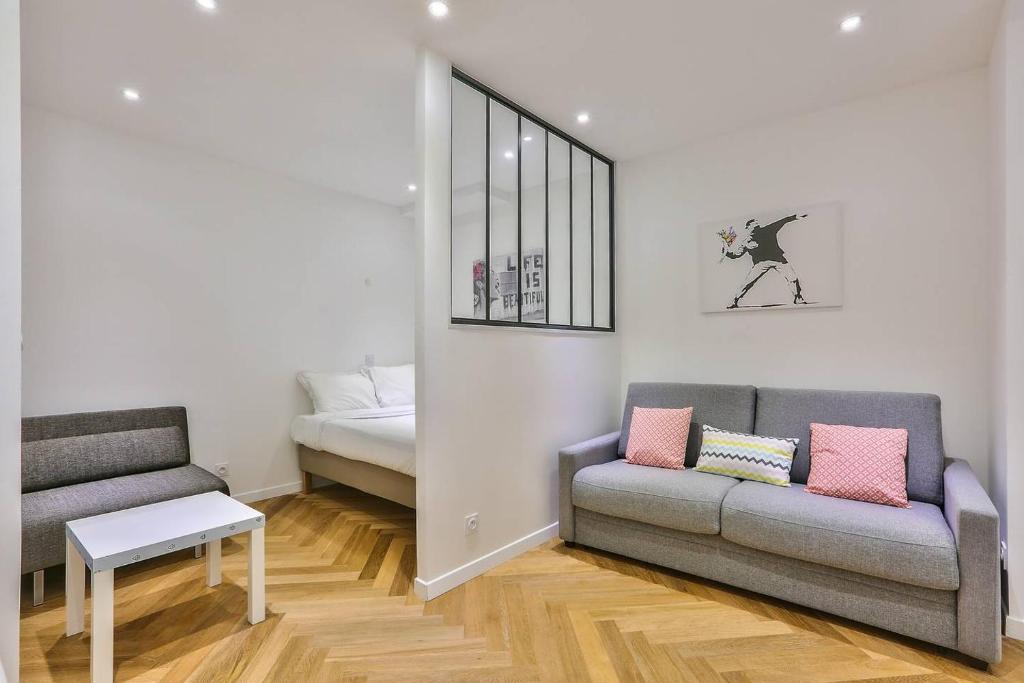 ein Wohnzimmer mit einem Sofa und einem Bett in der Unterkunft CMG Montorgueil/ Grands Boulevards in Paris