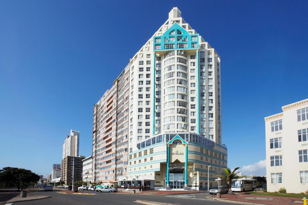 wysoki biały budynek z niebieskim dachem w obiekcie First Group The Palace All-Suite w mieście Durban