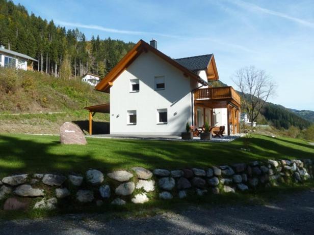 una casa blanca en una colina con una pared de piedra en Villa Vicana, en Kirchbach