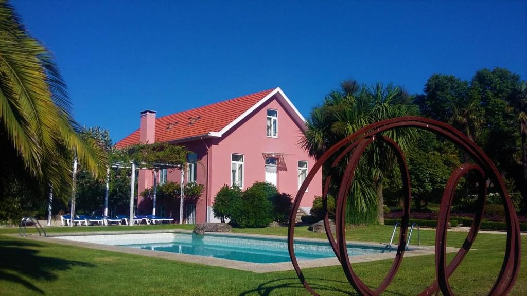 a pink house with a swimming pool in front of it at Casal do Arcebispado in Felgueiras