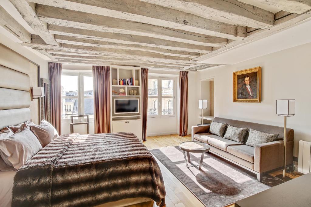 - une chambre avec un grand lit et un canapé dans l'établissement Luxury Apartment Paris Louvre, à Paris